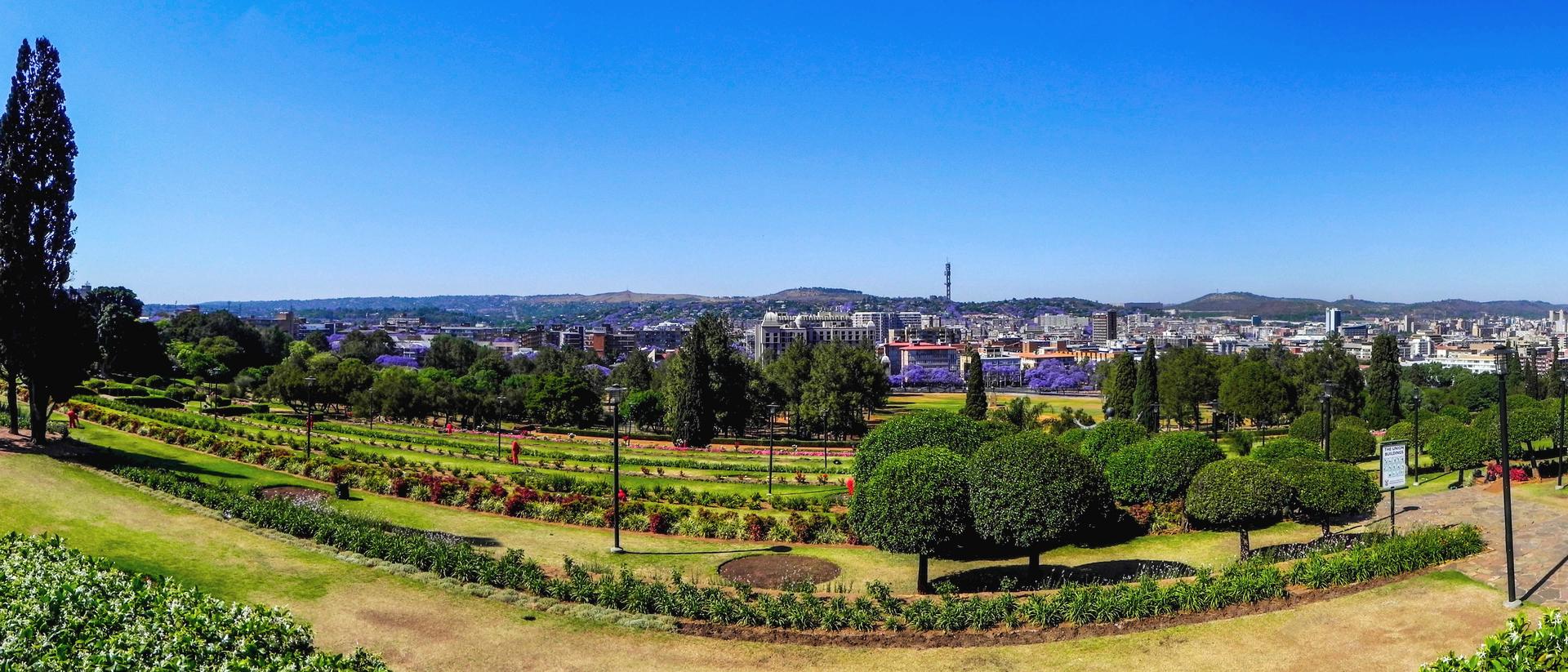 A wide view over the Pretoria city skyline from the gardens below the Union Buildings, with the city centre in the middle distance.
